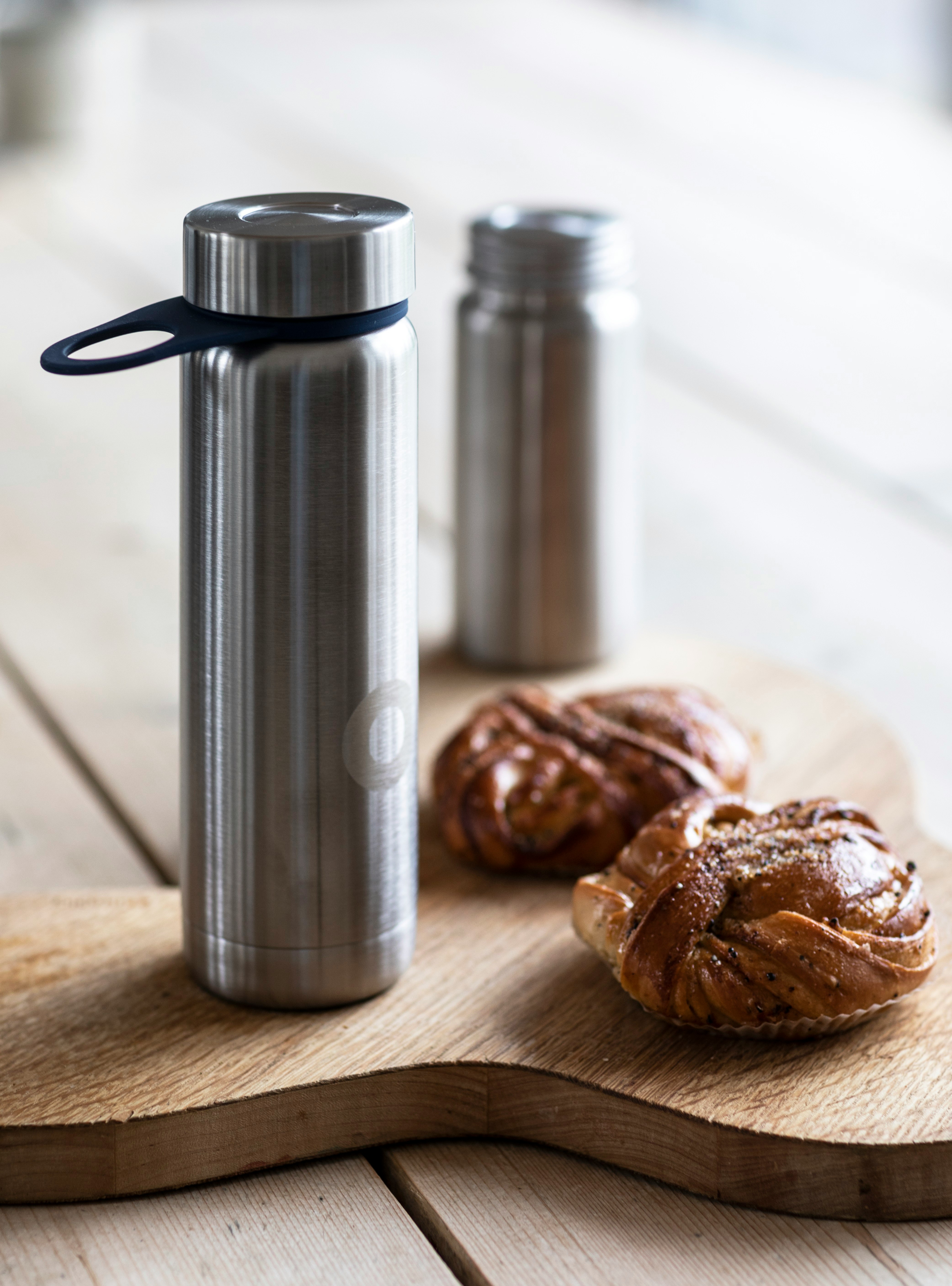 stainless steel vacuum flask beside brown cookies on brown wooden table